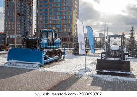 Bulldozer and wheeled tractor with mouldboard at an industrial exhibition at winter