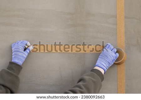 Hand holding off masking tape on wall. Masking Tape General Purpose DIY Painting. Home Renovation ideas. Home construction