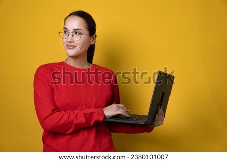 Photo of cute millennial lady hold laptop look up wear red outfit eyewear isolated on yellow color background. High quality photo