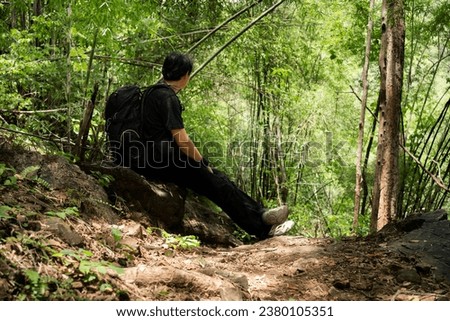 people activity concept with asian man hiking and use phone take picture in tropical forest