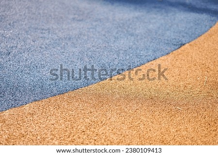 Special rubber coating for the playground or sports activity. Junction of multicolored pieces of floor covering made of recycled materials. Padded floor covering with rubber granules. Royalty-Free Stock Photo #2380109413
