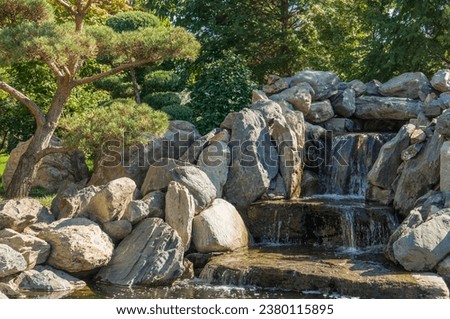 Krasnodar "Japanese Garden". Waterfall. Jets of water fall into stone bed of artificial river flowing into Mirror Lake Kagamiike or Mirror Lake (“kagami” - mirror). Krasnodar Park or Galitsky Park.