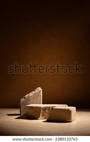 Stone podium, mock up for product cosmetic on dark beige background with dramatic light. Empty showcase for packaging presentation.