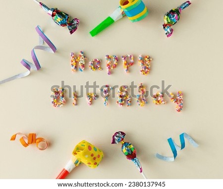 HAPPY BIRTHDAY message on cream background with candy letters and festive decoration. Copy space. Top view.