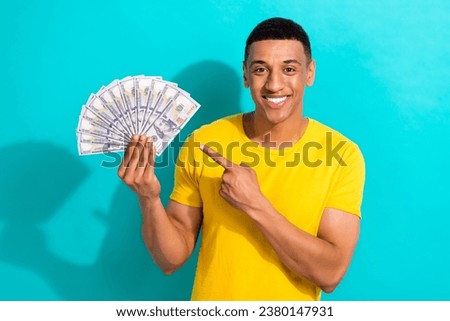 Photo of cute funky man dressed yellow t-shirt pointing finger money fan isolated turquoise color background