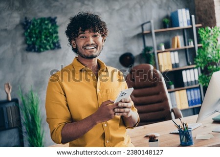 Photo of cheerful funny man dressed stylish shirt write sms hold iphone letter modern loft interior room indoors