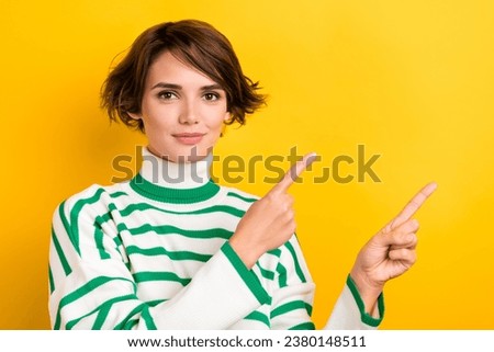 Photo of positive cute girl dressed striped sweater showing two fingers empty space isolated yellow color background
