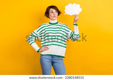 Photo of young model girl wear striped pullover denim jeans hold bubble empty space cloud dialogue isolated on yellow color background