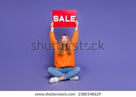 Full body length photo of youth teen girl wear orange pullover raised hands up demonstrate sale placard isolated on violet color background