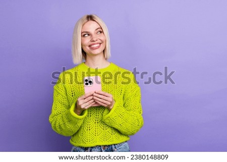 Photo of dreamy pretty lady wear green pullover texting modern gadget looking empty space isolated purple color background