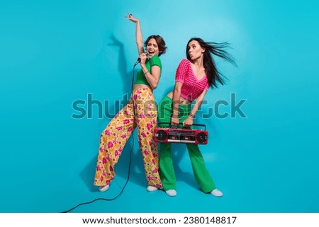 Full length photo of two youngsters female students spend summer weekend sing karaoke boombox sound check isolated on blue color background