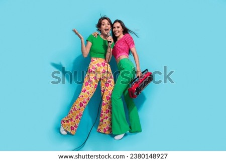 Two hippie girls relatives lesbians together couple lovers music addict sing microphone cassette recorder isolated on blue color background