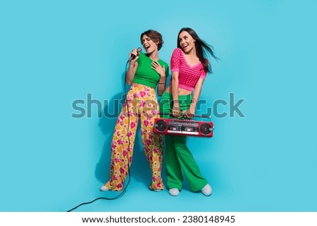 Full body cadre of two cute nice pretty young girls sing microphone karaoke party dreaming look novelty isolated on blue color background