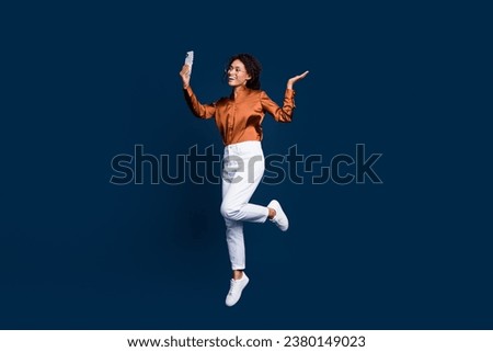 Full size photo of pretty young girl selfie jump video call dressed stylish brown silk formalwear isolated on dark blue color background