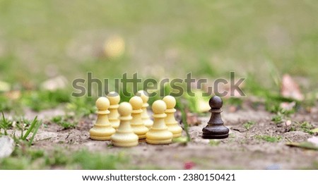 Symbol for excluding someone who is different. A group of white chess figueres is seperated from a single black figure. Royalty-Free Stock Photo #2380150421