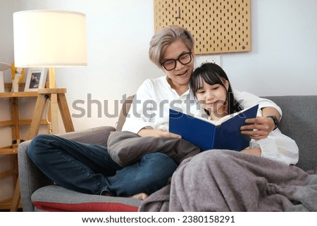Young couple reading book on sofa at home.