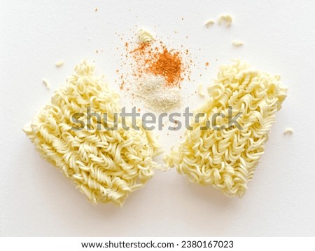 Instant noodles with seasonings on the table.  Uncooked noodles with dried red chilli flakes and ingredients on white.  Flat lay top view food photography.  Food from above concept.