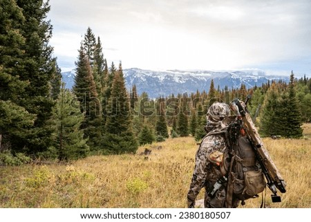 Man wearing camouflage, mule deer hunting inn Wyoming, in the mountains