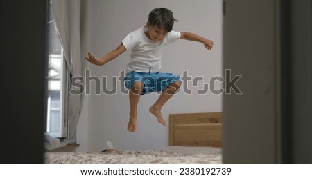 Excited happy child jumping up and down in bed in slow-motion. 1000 fps clip of little boy bouncing in bedroom Royalty-Free Stock Photo #2380192739