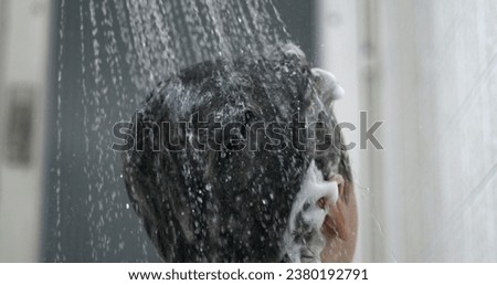 Water pouring into child's hair washing shampoo in super slow-motion, bathtime routine. Parent showering kid's head with shower head Royalty-Free Stock Photo #2380192791