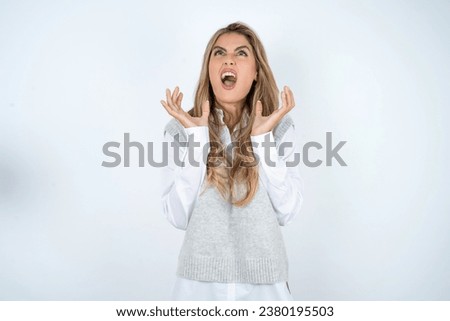 young beautiful woman crazy and mad shouting and yelling with aggressive expression and arms raised. Frustration concept.