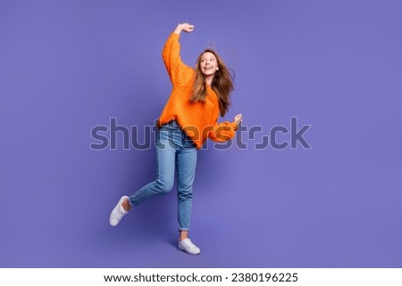Full length photo of young girl brown long hair dancing dressed halloween orange jumper raised hands up isolated on violet color background