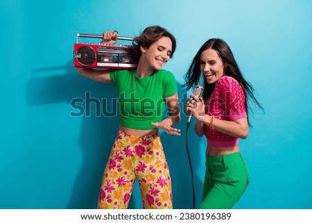 Photo of funky pretty girls dressed colorful outfits singing microphone listening boom box dancing isolated blue color background