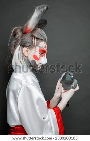Portrait of actress with makeup and costume holding bird on black background