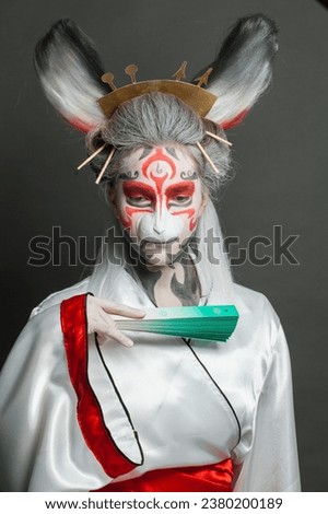 Actress woman with animal makeup, mask and stage asian costume posing on black background. Halloween, carnival, performance and theater concept