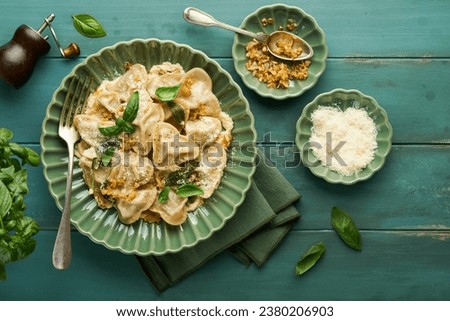 Homemade italian ravioli pasta in heart shape with beef meat, cheese sauce, caramelized onions, basil and saffron on old wooden blue background. Food cooking menu ingredients background. Top view. Royalty-Free Stock Photo #2380206903