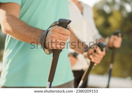Man practicing Nordic walking with poles outdoors, closeup Royalty-Free Stock Photo #2380209153