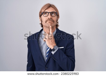 Caucasian man with mustache wearing business clothes thinking concentrated about doubt with finger on chin and looking up wondering  Royalty-Free Stock Photo #2380225983