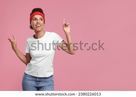 Happy young woman in stylish headband dancing on pink background. Space for text