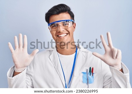 Hispanic man working as scientist showing and pointing up with fingers number eight while smiling confident and happy. 