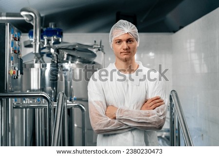 Portrait of a serious technologist in special uniform standing at a brewery with his arms crossed over his chest and looking at the camera Royalty-Free Stock Photo #2380230473
