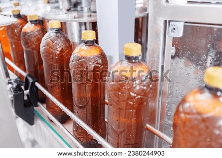 Brown plastic beer bottles moving on conveyor. Concept production line of brewery, modern food industry.
