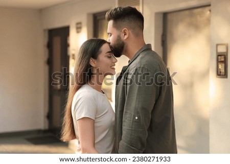 Long-distance relationship. Man kissing his girlfriend near house entrance outdoors Royalty-Free Stock Photo #2380271933