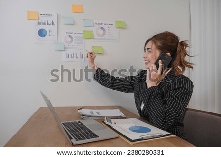 Asian businesswoman in a formal suit in the office is happy and cheerful while using a smartphone to work in her office.