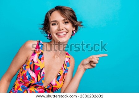 Photo of cheerful positive lady wear print clothes showing finger empty space isolated blue color background