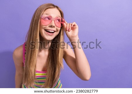 Photo portrait of pretty teenager blonde girl look empty space glasses dressed stylish striped outfit isolated on violet color background