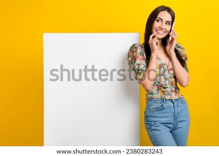 Photo of gorgeous positive girl dressed flower print blouse look at empty space talk on smartphone isolated on yellow color background