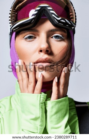 close up of pretty woman in active wear with balaclava on head looking at camera on grey background Royalty-Free Stock Photo #2380289711
