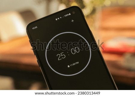 A phone with a black and white 25-minute timer to study with the pomodoro method on a blurry background
