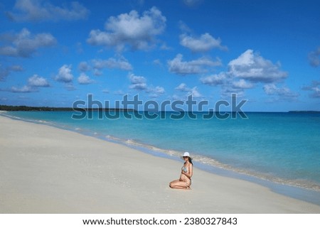 Pregnant woman sitting at Fayaoue beach on the coast of Ouvea lagoon, Mouli and Ouvea Islands, New Caledonia. The lagoon was listed as Unesco World Heritage site in 2008.