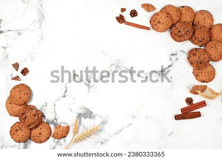 Freshly baked homemade oatmeal cookies with chocolate chips and gluten free nuts with ears on marble background,modern bakery and grain food concept.Healthy breakfast with ingredients,top view,