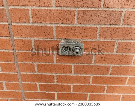 A closeup of a hookup on the outside of a brick wall.