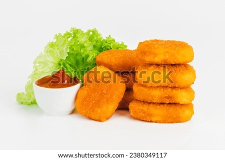 Breaded Chicken Inner Fillet with green lettuce leaves on a White Background,Chicken Breaded Raw Meat,Fillet.Breaded chicken nuggets. Fast homemade food at home.Chicken breaded schnitzels.Fast cooking
