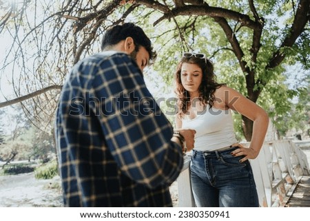 Joyful friends, a man and woman, relax in a sunny park, enjoying nature. They have fun, positive conversations and soak up the carefree, playful atmosphere of their weekend activities. Royalty-Free Stock Photo #2380350941