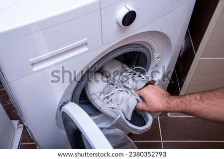 Top view of putting dirty old sneakers into washing machine