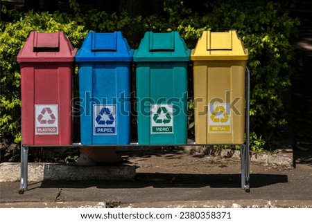 Four color trash cans for recycling, with the words Plastic, Paper, Glass and Metal in Portuguese on the park in Brazil Royalty-Free Stock Photo #2380358371